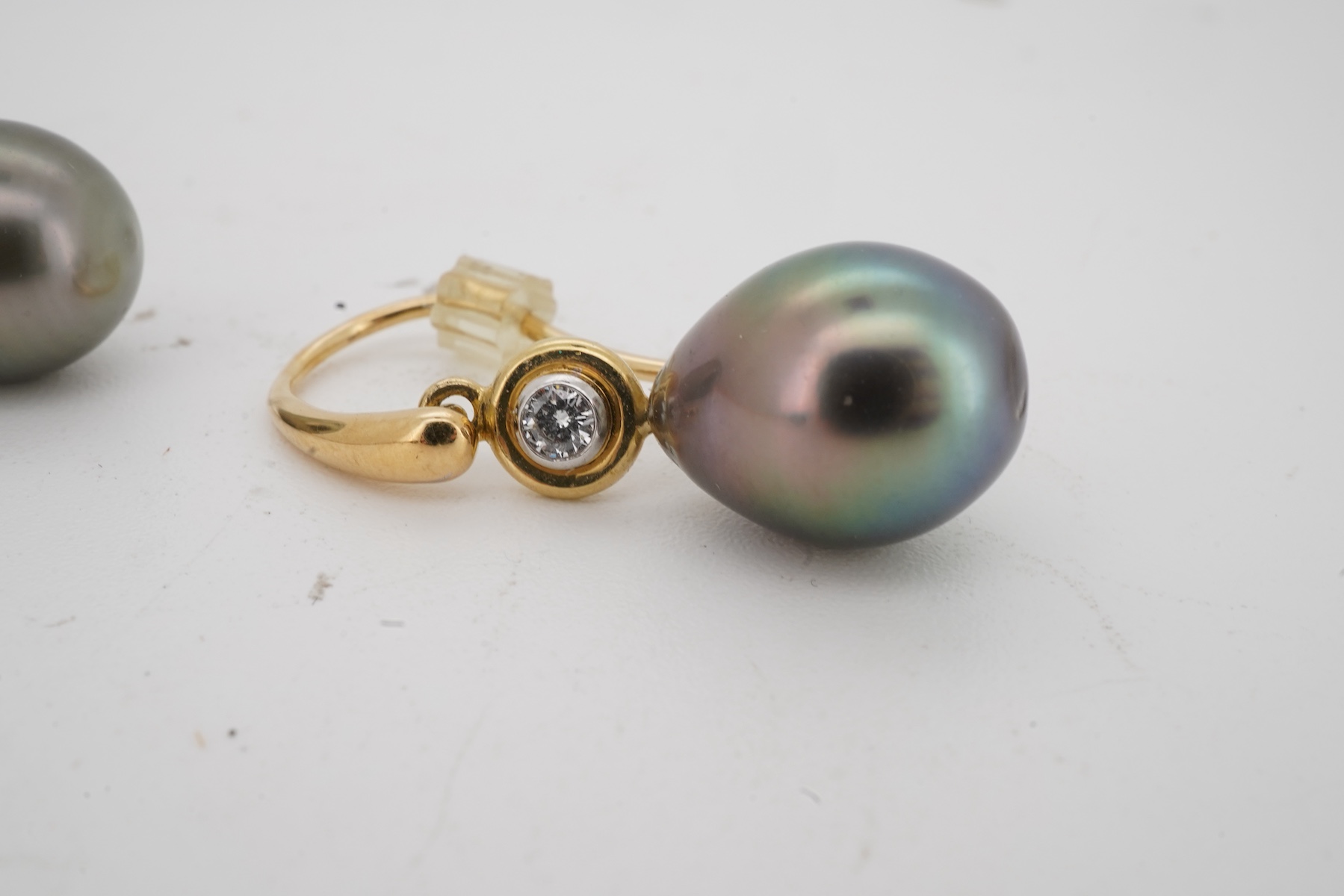 A cultured pearl and diamond demi-parure, comprising: a pendant, suspending a drop-shaped cultured pearl of black tint, measuring approximately 15 x 10.5 x 10.5mm, surmounted by a collet-set brilliant-cut diamond weighin